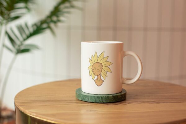 white mug with delicate illustration of a moon rock and sun flower personified.